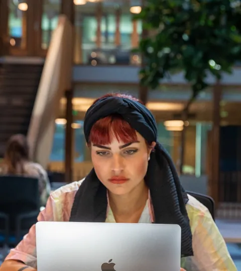Een student is aan het werk op haar laptop op de campus van de Radboud Universiteit.