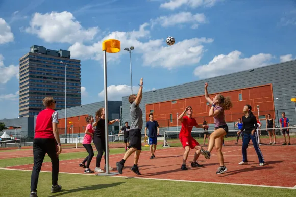Groep studenten die buiten korfbal speelt op de velden van het sportcentrum