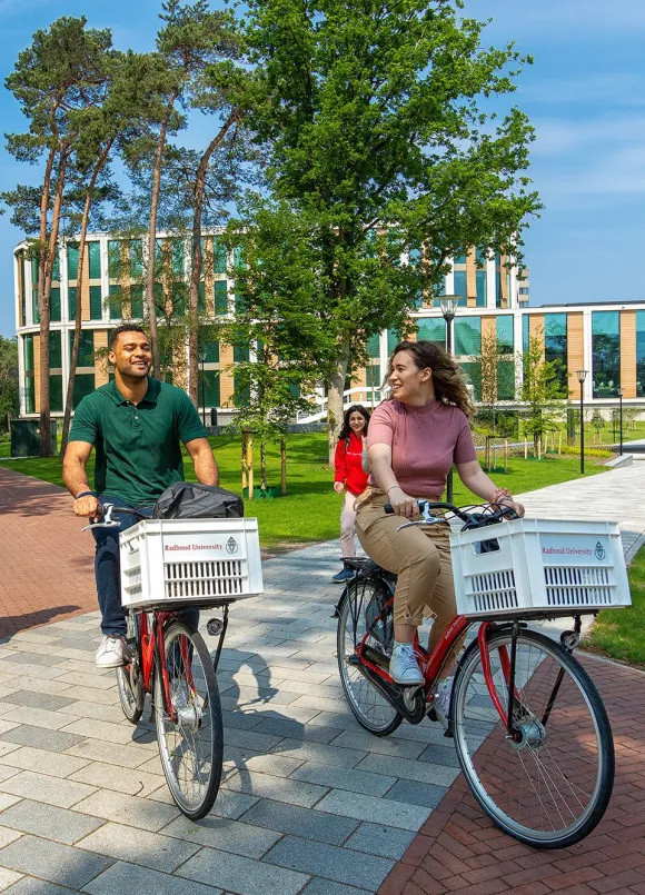 Twee studenten fietsen over de campus van de Radboud Universiteit
