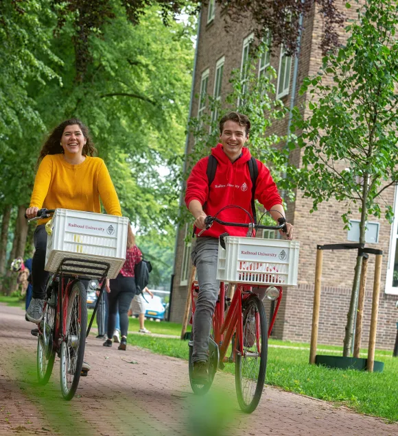 Twee studenten fietsen over de campus van de Radboud Universiteit