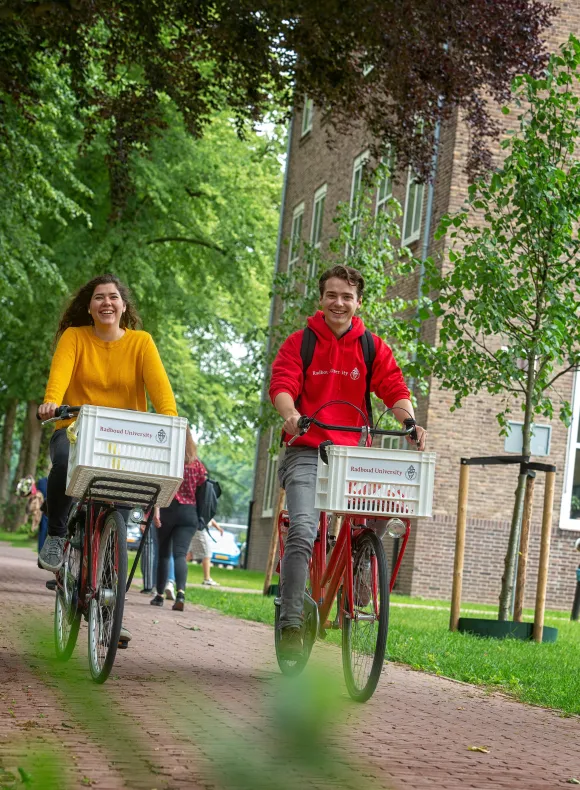 Twee studenten fietsen over de campus van de Radboud Universiteit