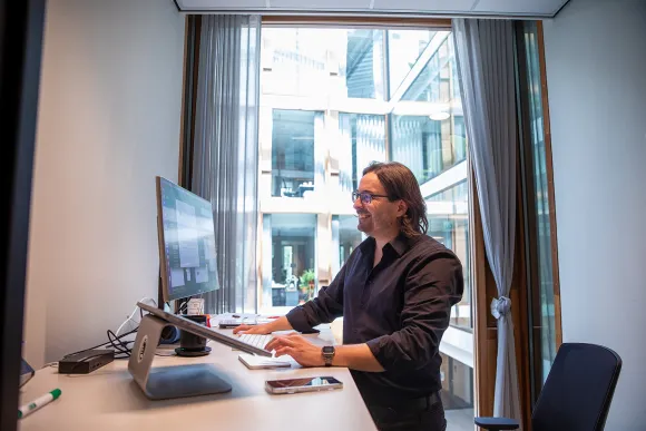 Giulio staat in zijn bureau achter zijn laptop