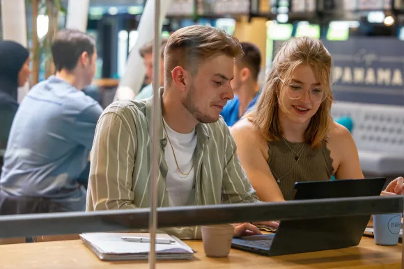 Studenten achter een laptop in de Refter op de Radboud Universiteit.