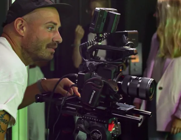 A man wearing a cap looking through the lens of a camera