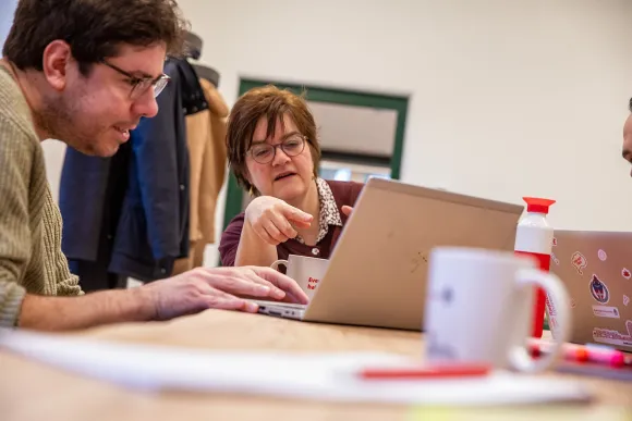 Een man en een vrouw overleggen voor een laptop