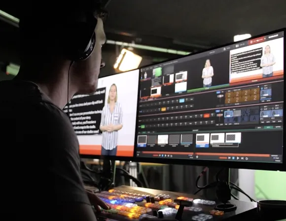 A man wearing headphones sitting in front of two computer screens while editing a video.