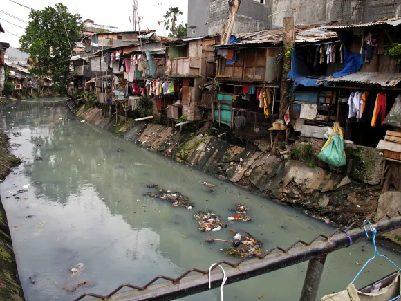 Slum housing next to a polluted stream in Indonesia