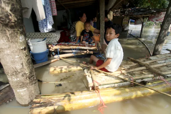 A family shelter in their partly submerged wooden hut in Indonesia