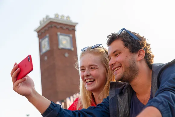 Studenten die een foto nemen voor het centraal station in Nijmegen