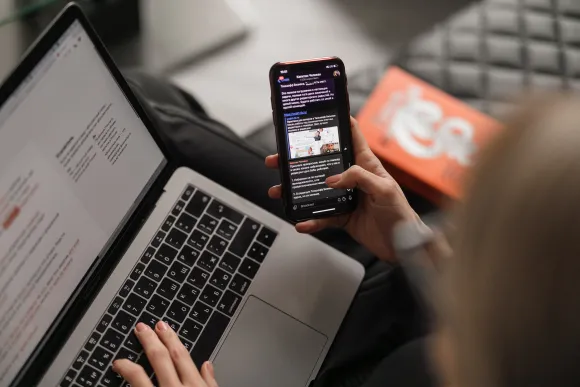A person looking at their phone and laptop.