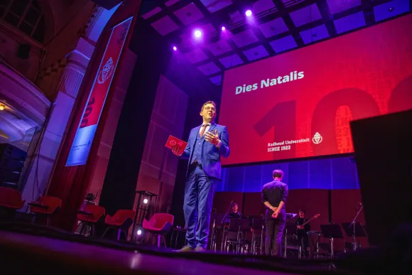 Campusdichter Thijs Kersten staat op het podium van de 100e Dies Natalis