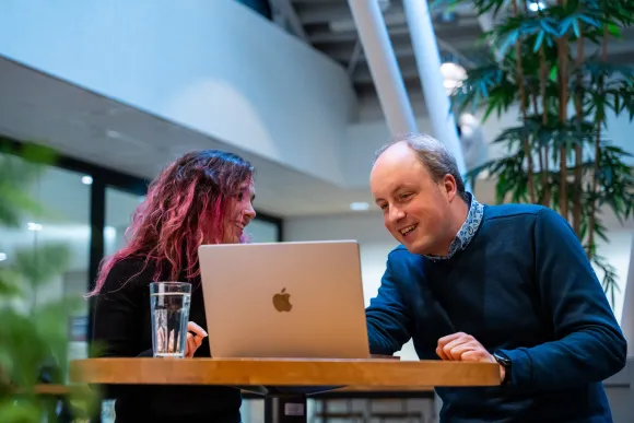 Twee collega's werken samen aan een laptop