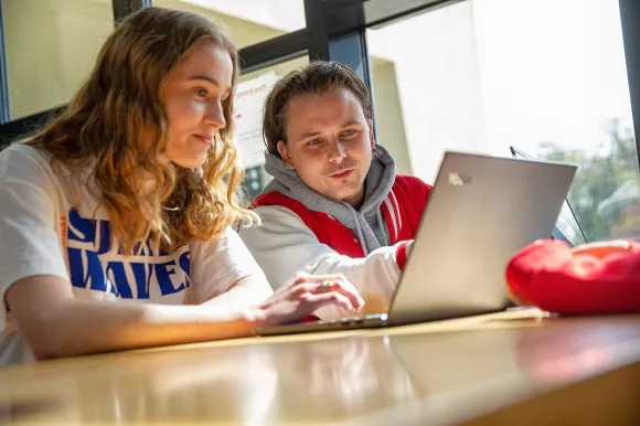 Studenten samen aan het werk op een laptop.