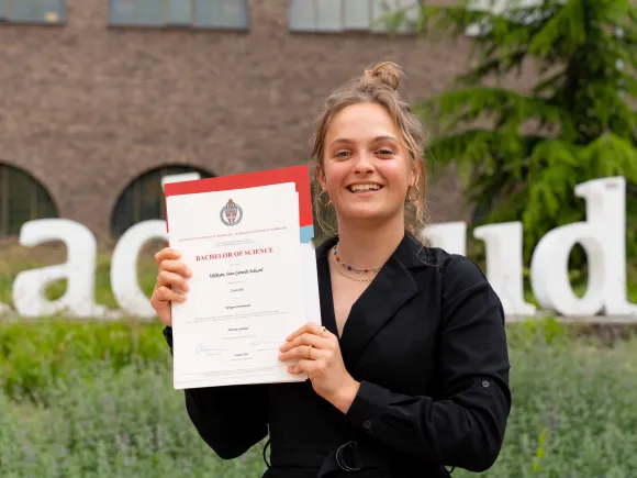 Student Suus volgde extra vakken over duurzaamheid en behaalde een duurzaamheidsgetuigenis op haar bachelordiploma. Ze poseert trots met haar diploma.