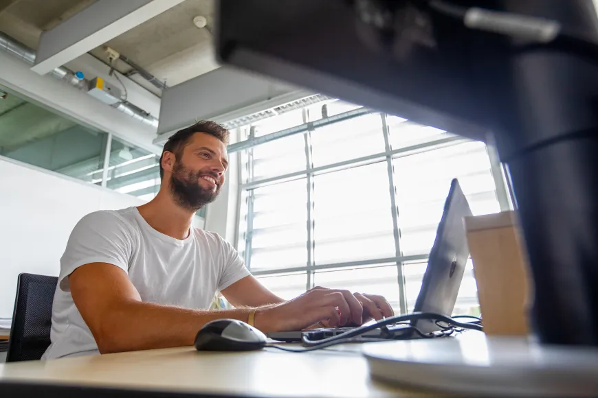 Een man voor een computer aan het werk