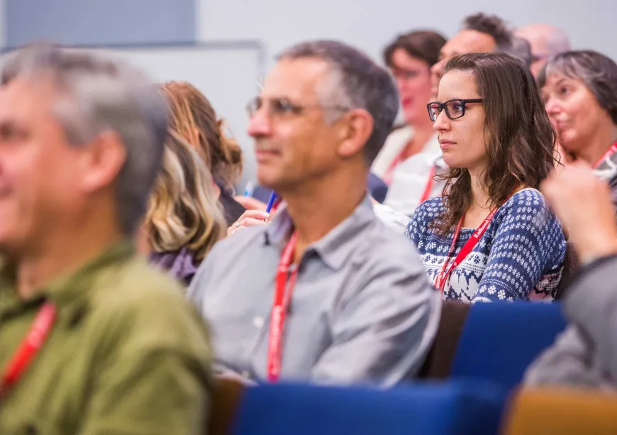 Foto van mensen die aandachtig luisteren bij een lezing
