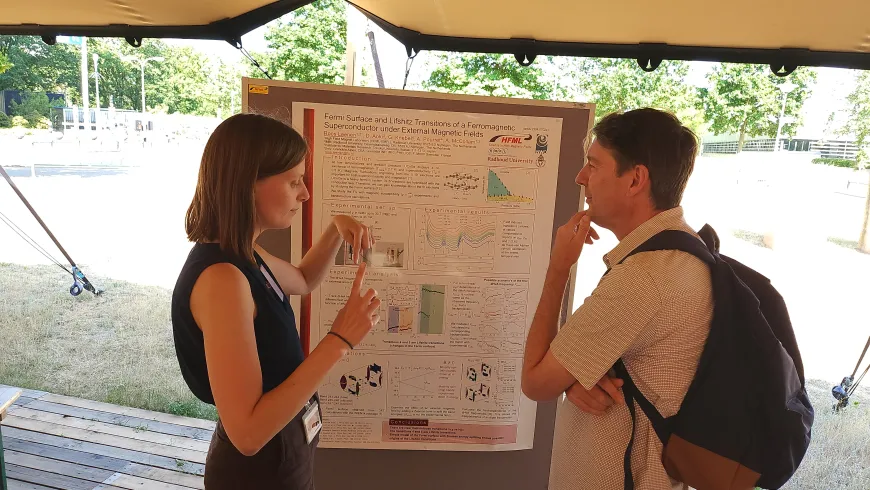 PhD-student and attending researcher discussing poster outside.