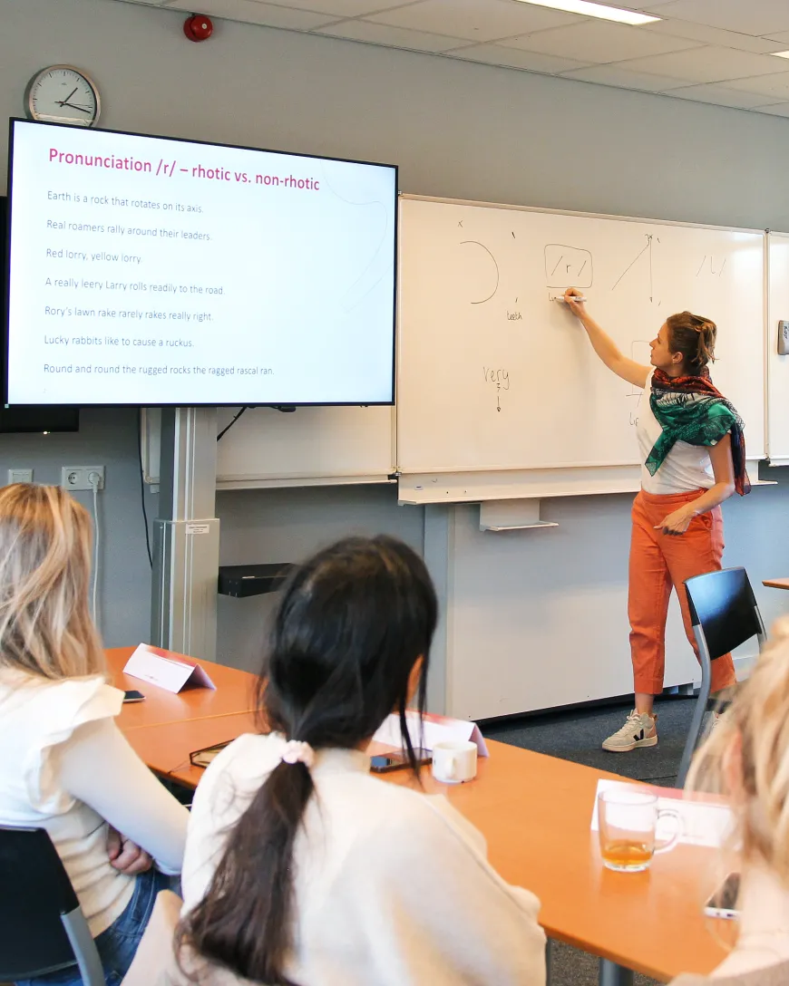Docent schrijft op een whiteboard in een leslokaal