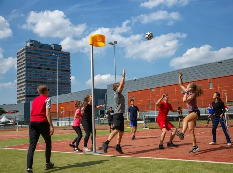 Groep studenten die buiten korfbal speelt op de velden van het sportcentrum
