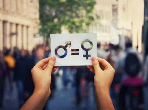 Two hands holding card with gender signs on it.