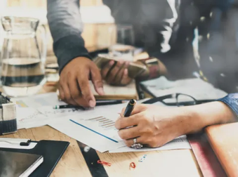 Man writing on paper with economy graphs