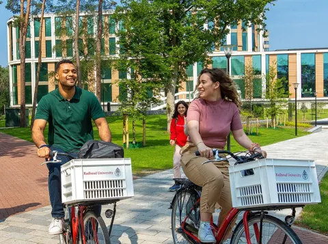 Twee studenten fietsen over de campus van de Radboud Universiteit