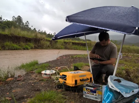 Foto van een watergebied in Brazilie met een onderzoeker die metingen uitvoert ernaast