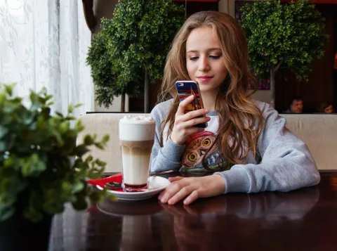 Jonge vrouw met smartphone en koffie
