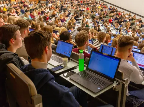Studenten in een collegezaal met laptops open