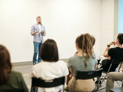 Man geeft lezing in zaaltje met mensen