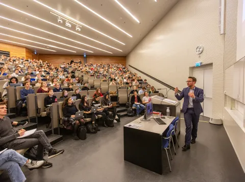 Volle collegezaal met professor voor de zaal
