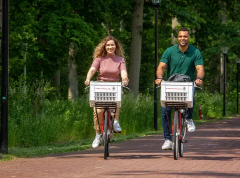 Twee studenten fietsen over de campus van de Radboud Universiteit