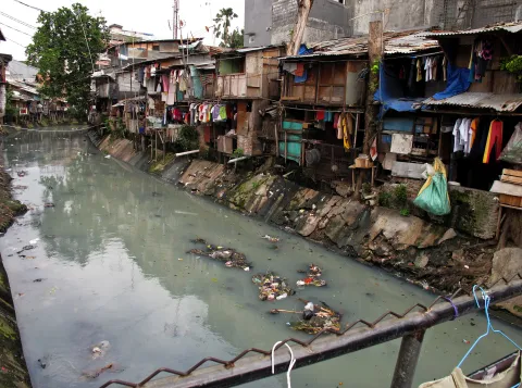 Slum housing next to a polluted stream in Indonesia