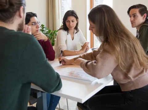 Kleine groep studenten die aan tafel zitten