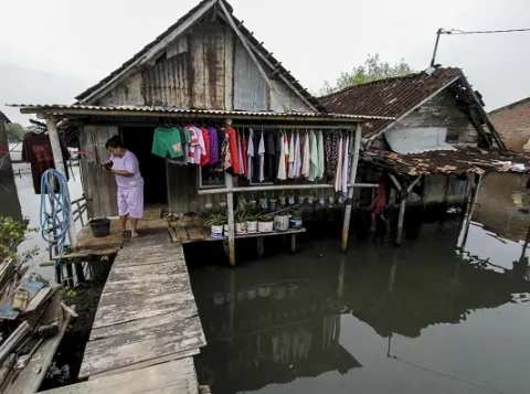 Woman tends to washing hanging on the porch of her wooden shack on stilts in Indonesia
