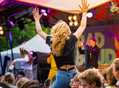A girl sitting on someone's shoulders enjoying a festival