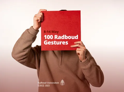 Person holding a Radboud gebaren poster