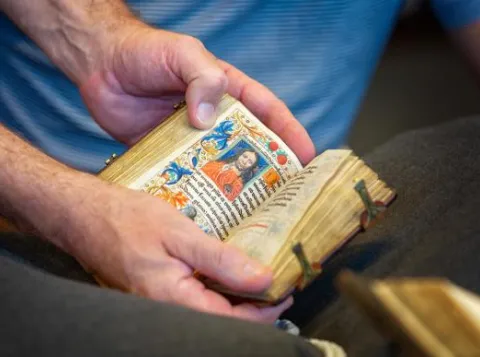 Een persoon houdt een historisch boek in zijn handen