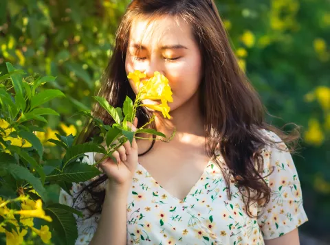 A woman smelling a yellow rose