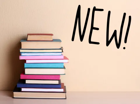 Een stapel gekleurde boeken met daarnaast de tekst "New!"
