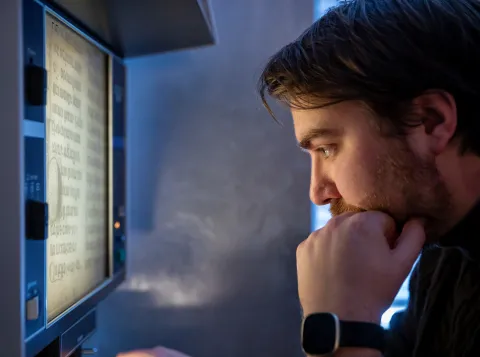 Onderzoeker bekijkt oude teksten via microfilmlezer