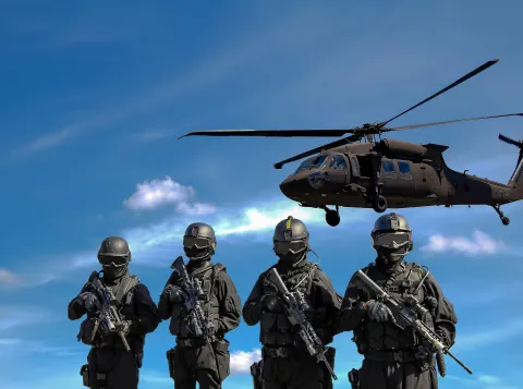 vier soldaten met geweren voor een helicopter