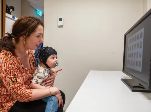 Moeder met baby op schoot kijkend naar een computer