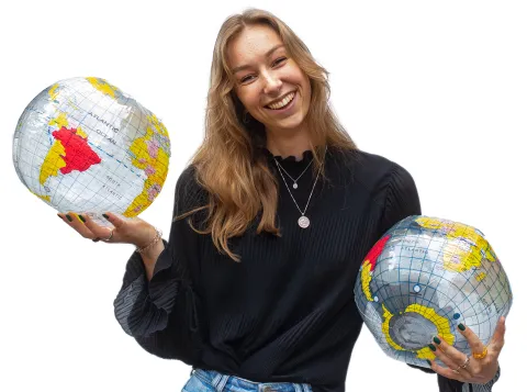 Een foto van een lachende studenten met twee opgeblazen plastic wereldbollen in haar handen