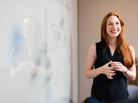 Vrouw geeft een presentatie naast een whiteboard