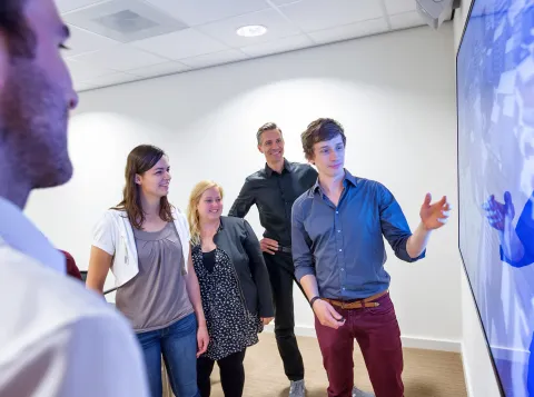Foto van meerdere personen naast een smartboard