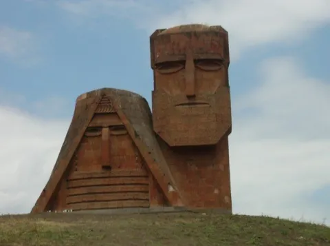 A monument consisting of two large faces made of stone called "We are our mountains".