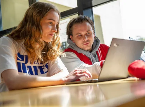 Studenten samen aan het werk op een laptop.