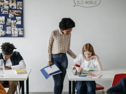 Vrouwelijke docent helpt leerling in de klas