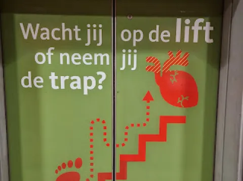 Liftdeur met opschrift 'Wacht jij op de lift of neem jij de trap?'